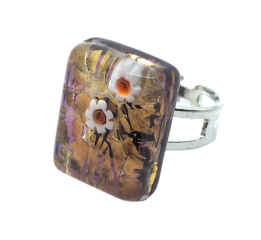 The Murano Passion Murano Glass Ring features a stunning rectangular design measuring 2cm x 1.5cm. Crafted with genuine Murano glass, the ring is adorned with intricate millefiori flowers set against a backdrop of swirling gold leaf and purple patterns. Handmade in Venice, this piece embodies elegance and artistry.