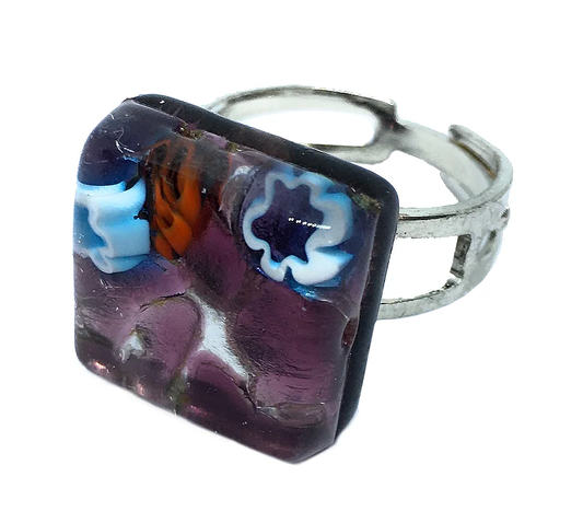 This exquisite piece, crafted by Murano Passion, is an adjustable ring featuring a square purple glass decoration with blue, white, and orange floral patterns. It is made from genuine Murano Glass and is the "Murano Glass Ring, Millefiori Ring on Silver Leaf - Dainty 1.5cm.