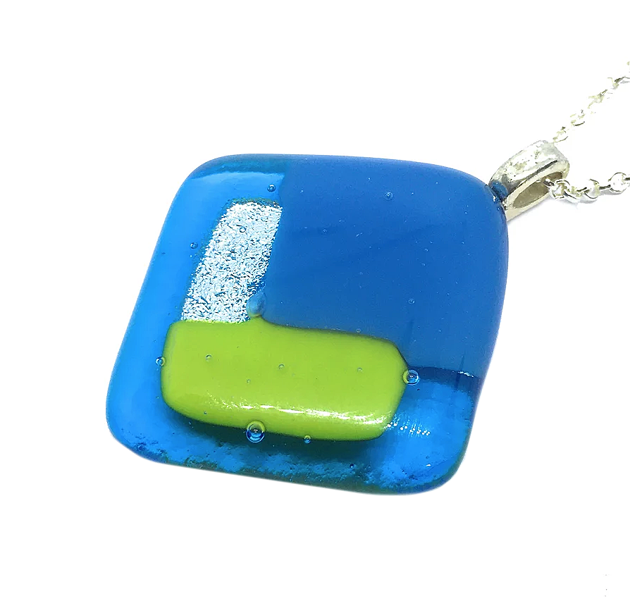 The Handmade Dichroic Glass Pendant by Calon Glass features an exquisite square design, showcasing layered hues of blue, green, and silver. Expertly kiln-fused, this 3cm x 3cm pendant elegantly suspends from a silver chain for a captivating look.