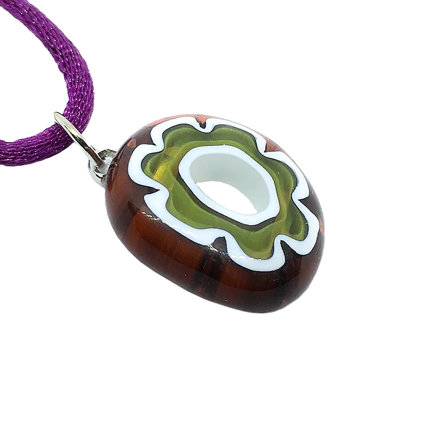 Introducing the Murano Passion Murano Glass Pendant, crafted with a captivating Millefiori Flower design. Measuring 2cm by 1.5cm, this exquisite piece showcases an abstract blend of white, green, and brown shapes. Hanging from a striking purple cord, the pendant's oval shape and central opening highlight the artistry of Murano glass and enhance its unique allure.