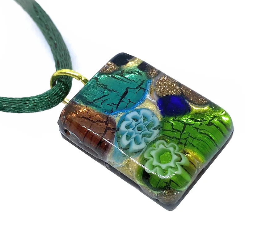 The Murano Passion Murano Glass Pendant on Gold Leaf, measuring a dainty 2cm x 1.5cm, features a vibrant glass design on a green cord. This elegant piece includes blue, green, and brown abstract patterns with floral-like details at its center, enhanced by gold accents and layered textures, exemplifying the exquisite craftsmanship of Murano Glass Jewellery.