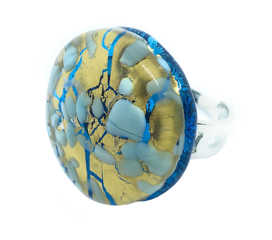 The Murano Passion ring is a chunky statement piece featuring a round, flat stone with a captivating mosaic pattern of gold, blue, and beige hues. It's crafted from authentic Murano glass and elegantly set in a silver band.