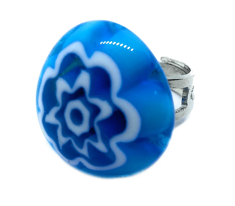 The Murano Passion Murano Glass Ring features a silver band and showcases a large, round blue resin top that is elegantly adorned with an abstract, floral-like white pattern in the center, embodying Venetian artistic heritage.