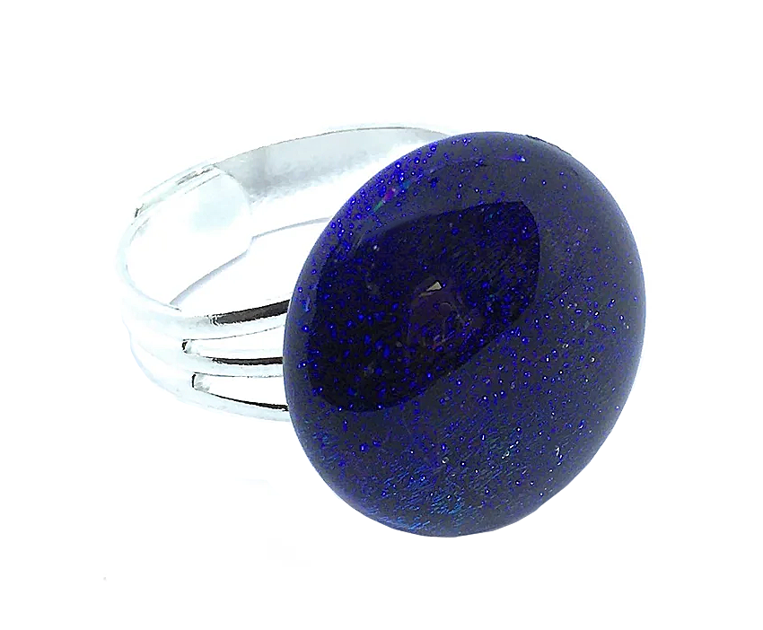 The Handmade Dichroic Glass Ring by Calon Glass is a stunning silver-plated piece featuring a large, round, glossy dark blue dichroic glass stone with specks. The adjustable band, crafted from three slender parallel lines that merge seamlessly, beautifully supports the 1.7 cm stone against a plain white background.