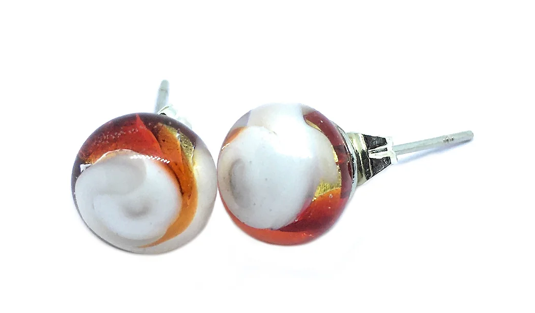 These Murano Glass Stud Earrings from Murano Passion showcase intricate swirling patterns in white, orange, and brown hues. Featuring metallic posts and a glossy finish, they exemplify exquisite craftsmanship. Each 8mm pair includes a Certificate of Authenticity to guarantee their status as genuine Murano Glass Jewellery.