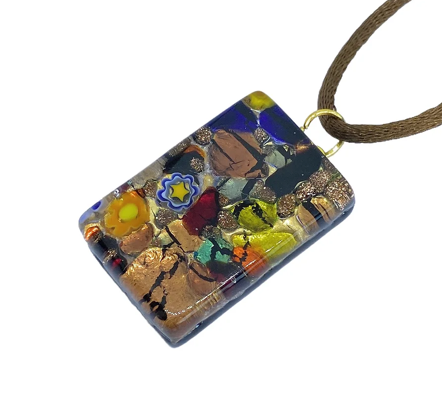 The Murano Glass Pendant, Millefiori on Gold Leaf - 3cm x 2cm from Murano Passion is a stunning mosaic of multicolored patterns, featuring abstract shapes and floral designs in vibrant shades of blue, yellow, red, and metallic tones. It gracefully hangs on a brown cord and comes with a Certificate of Authenticity.