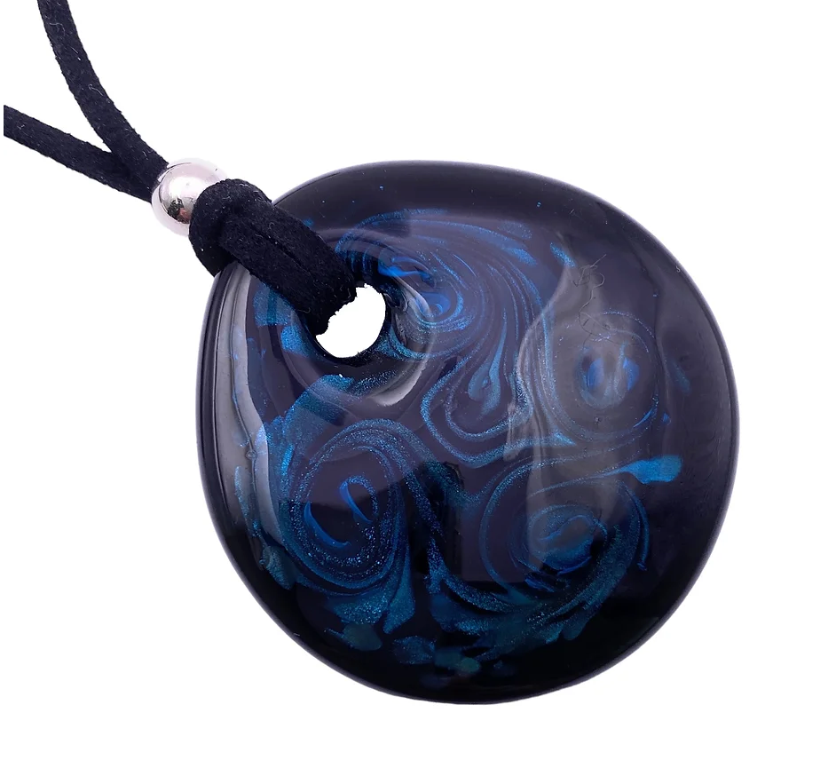 The Murano Passion "Murano Glass Aventurine Pendant in Blue" is a stunning glossy black piece measuring 5.5cm by 5cm. It features swirling blue and gray patterns and hangs elegantly from a black cord, accented with a small silver bead. This oval-shaped pendant, reminiscent of classic Murano Glass Jewellery, includes a circular hole near the top for the cord.