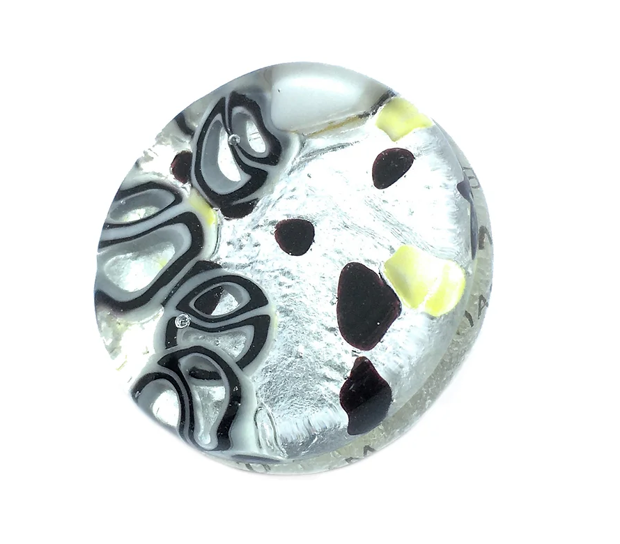 A Murano Glass Brooch from Murano Passion, measuring 2.4 cm and crafted on a silver leaf base, exudes an artistic flair similar to Venice, Italy's renowned Millefiori art. The brooch boasts intricate abstract patterns in black, white, and yellow with swirls and dot-like shapes that mimic a metallic sheen and textured appearance.