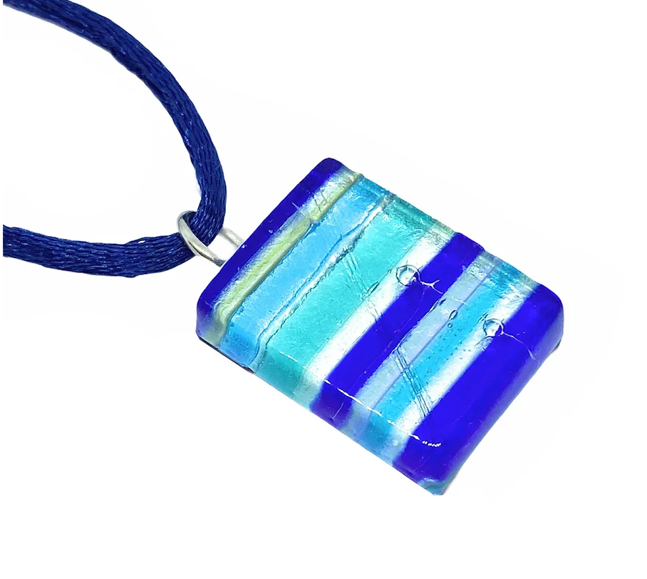 This Murano Passion necklace, named Murano Glass Pendant on Silver Leaf - Dainty 2cm x 1.5cm, showcases a rectangular pendant adorned with horizontal stripes in vibrant shades of blue, white, and light yellow. The exquisite pendant is elegantly attached to a dark blue cord and is accompanied by a Certificate of Authenticity.