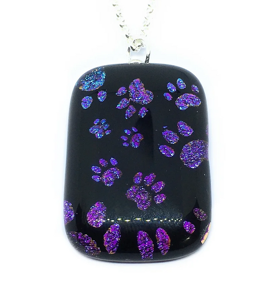 Calon Glass presents a distinctive rectangular black pendant with a silver chain, adorned with scattered purple glitter paw prints, expertly crafted from handmade dichroic glass.