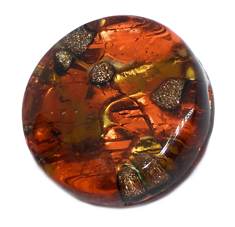 Featured against a white background is the Murano Glass Brooch with a Gold Leaf Base from Murano Passion. This round, amber-colored cabochon boasts abstract metallic details and swirling patterns with inclusions that evoke Venetian heritage, offering a textured appearance ideal for a statement brooch.