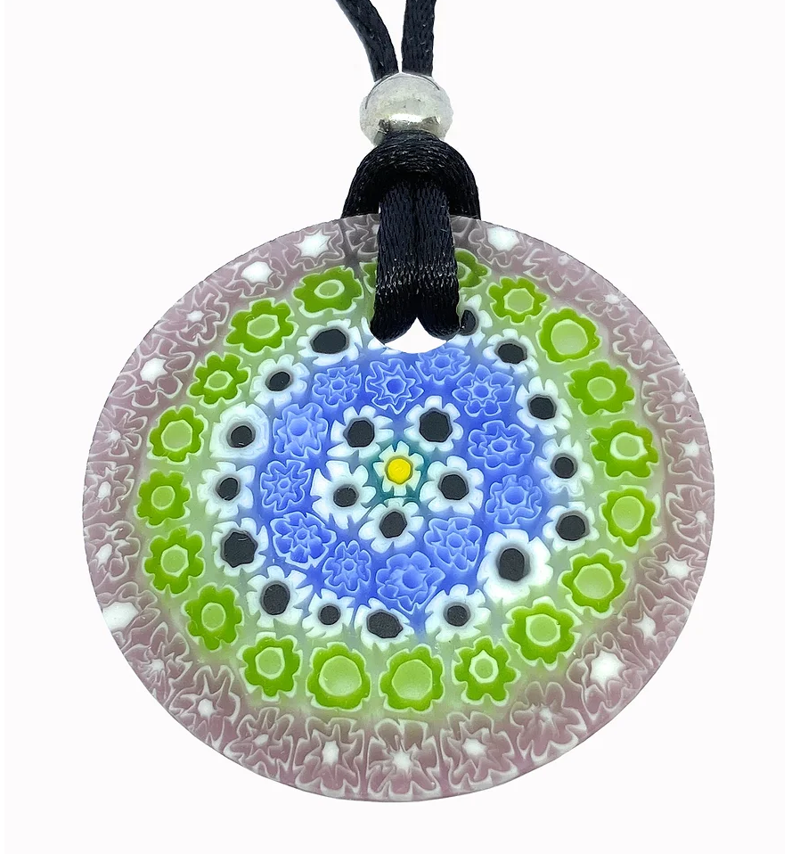 The Murano Passion Pendant is a round 4cm Murano Glass piece, crafted with Millefiori Flowers. It features a design of concentric circles adorned with colorful flowers in shades of blue, green, and pink, reflecting the rich Venetian artistic heritage. This elegant piece is suspended from a black cord.