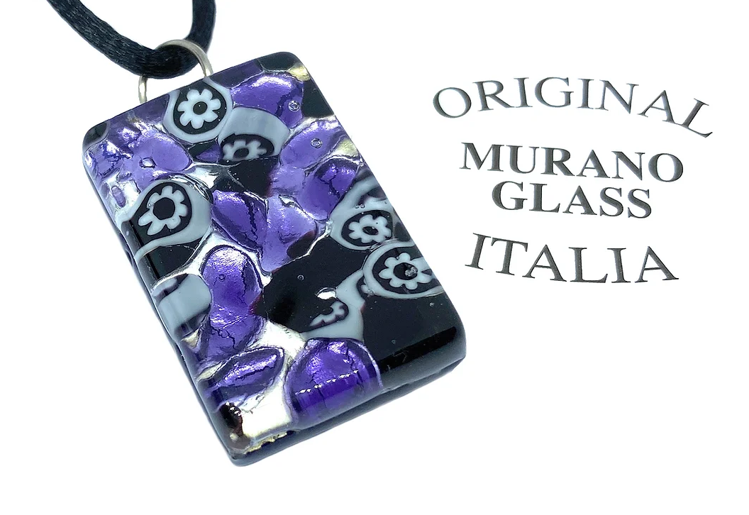 This Murano Glass Pendant, measuring 3cm by 2cm and featuring a Millefiori design on silver leaf, hangs elegantly from a black cord. Its vibrant purple, white, and black floral patterns highlight its exquisite artistry. The accompanying text asserts "Murano Passion," underscoring its authenticity as genuine Murano Glass craftsmanship.