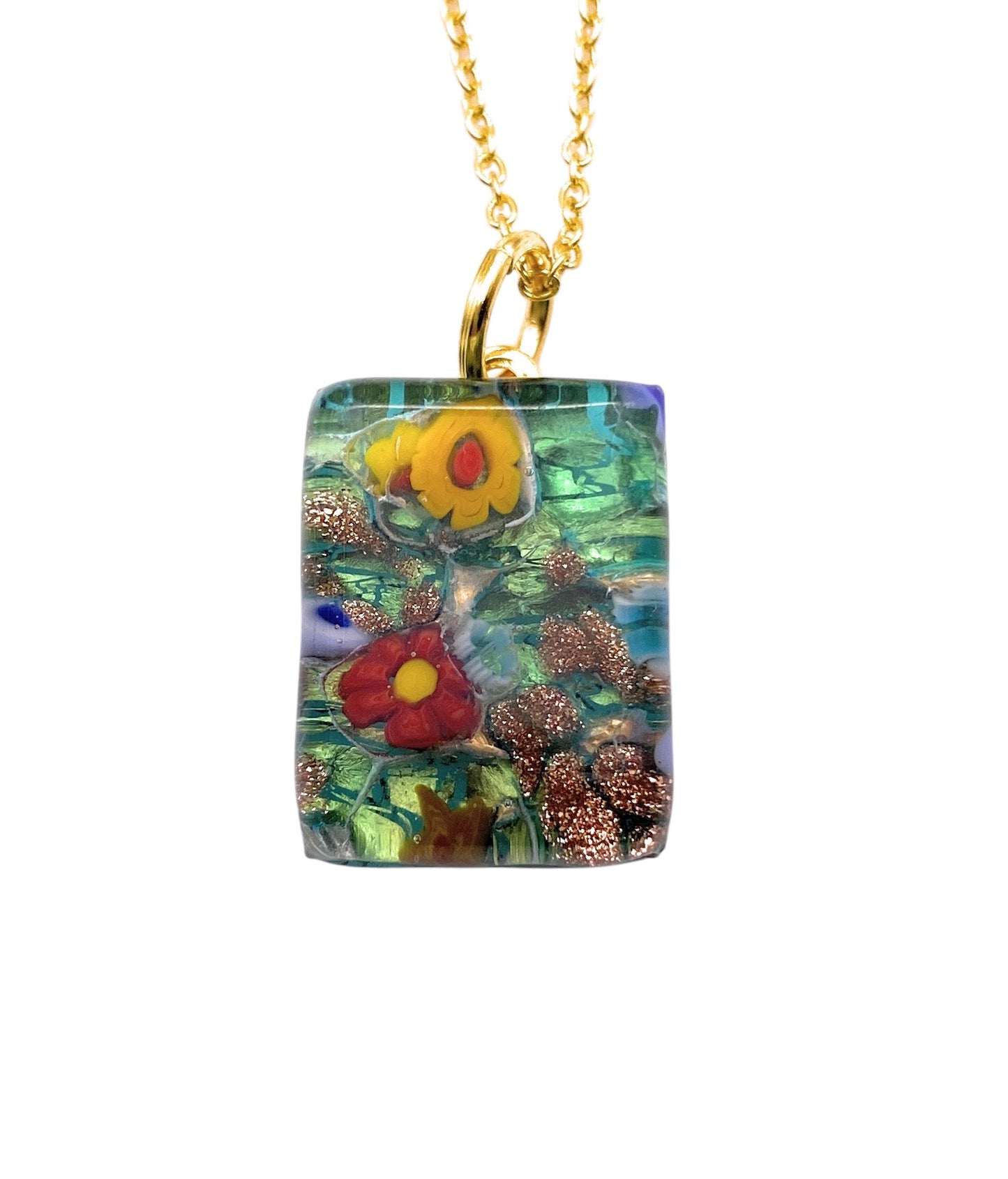 Introducing the Murano Passion Millefiori Flower Pendant, a captivating piece featuring an abstract floral design in vivid red, yellow, and green hues on a rectangular Murano glass. This dainty 2cm x 1.5cm pendant (MGPP8) is elegantly suspended from a gold chain, making it a stunning addition to any collection.