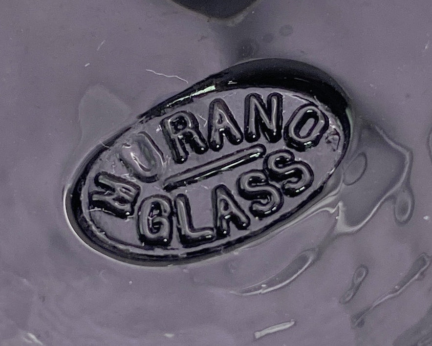 Close-up image of an oval label with raised letters reading "Murano Passion" against a glossy black background, reminiscent of the Murano Glass Aventurine Pendant in Blue.