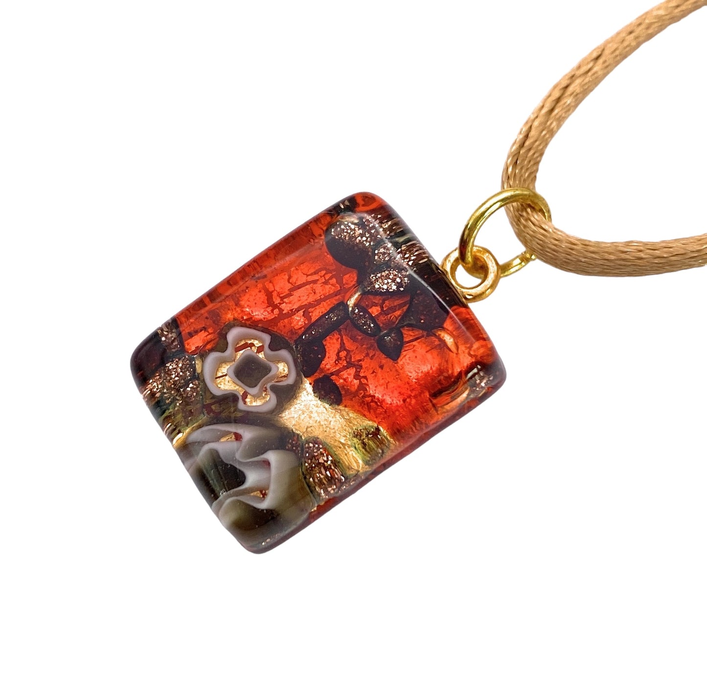 Introducing the Murano Passion "Murano Glass Pendant, Millefiori Pendant on Gold Leaf - Dainty 2cm x 1.5cm (MGPP26)," a striking square-shaped piece adorned with a gold loop and complemented by a tan cord. This exquisite pendant showcases intricate floral patterns intricately crafted in red, gold, and black hues. It is accompanied by a Certificate of Authenticity to guarantee its genuine craftsmanship.